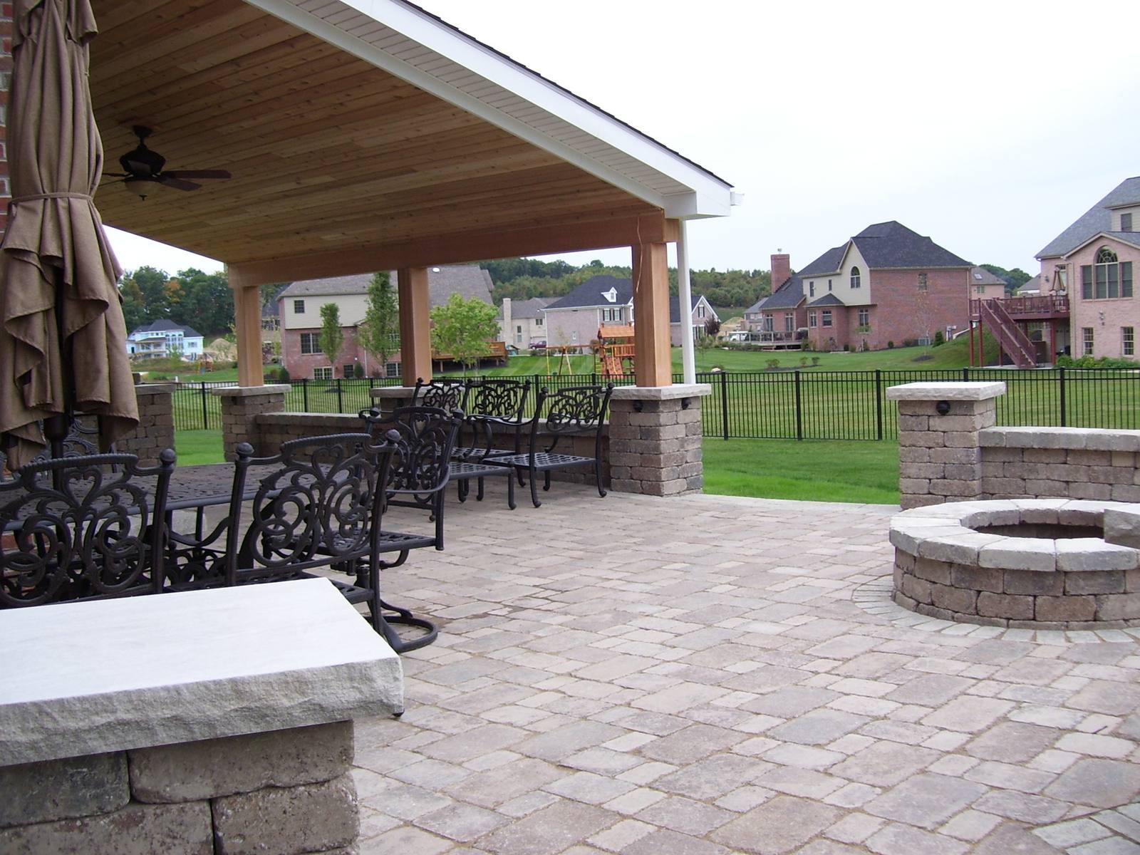 Paver patio with a fire pit and a covered seating area, from a Hannan Construction outdoor living project.